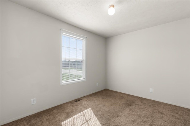 empty room with carpet, a textured ceiling, and visible vents