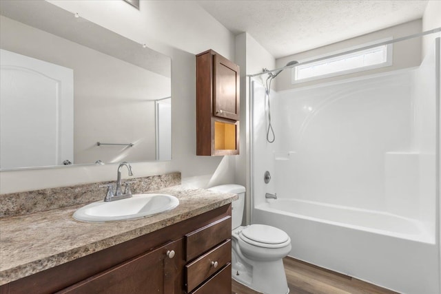 full bathroom featuring vanity, toilet, bathtub / shower combination, a textured ceiling, and wood finished floors