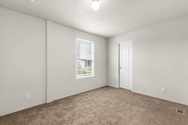 carpeted spare room featuring a textured ceiling, baseboards, and visible vents