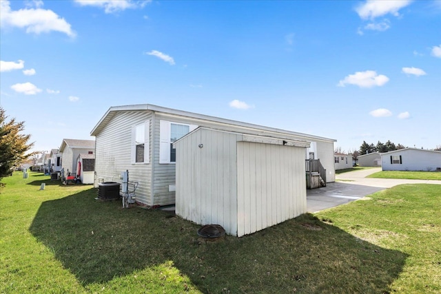 view of side of home featuring an outbuilding, central AC, and a yard