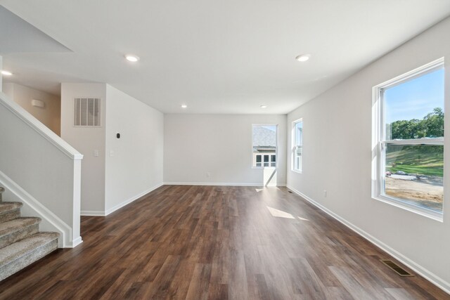 unfurnished living room with visible vents, stairs, dark wood-type flooring, and baseboards