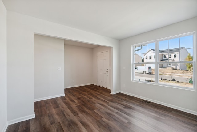 spare room featuring baseboards, visible vents, and dark wood-type flooring