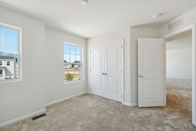 unfurnished bedroom featuring visible vents, carpet, and baseboards