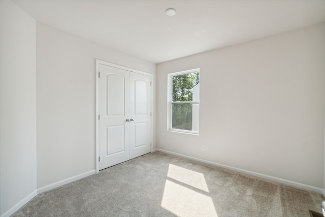 unfurnished bedroom with carpet floors, baseboards, and a closet