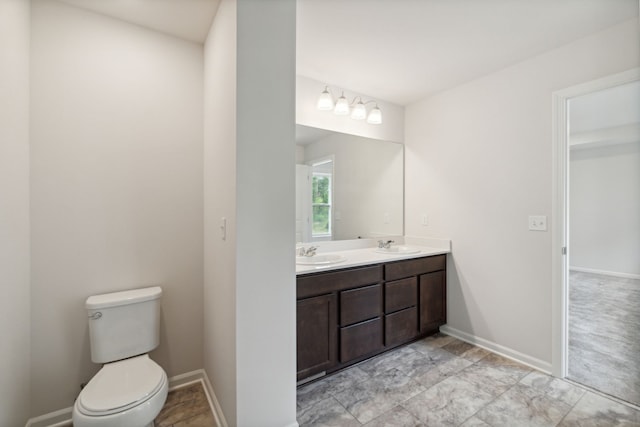 full bath featuring double vanity, a sink, baseboards, and toilet