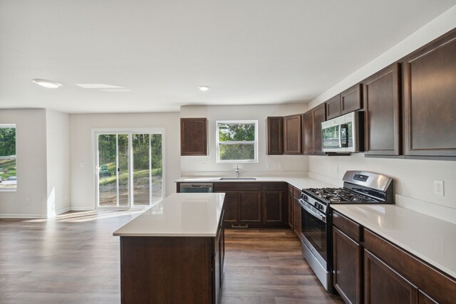 kitchen featuring dark brown cabinets, appliances with stainless steel finishes, a sink, light countertops, and dark wood-style floors