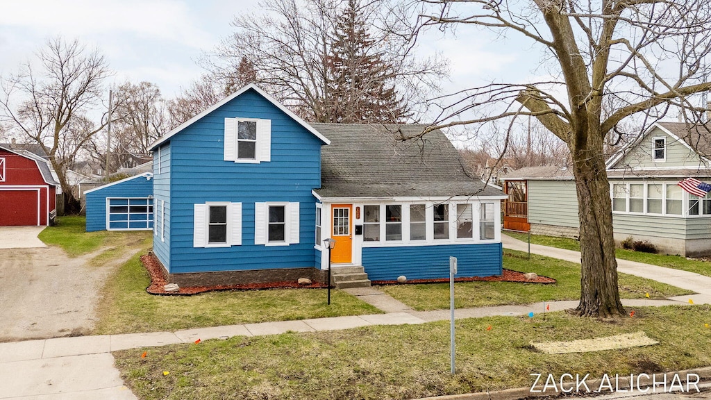 520 Monroe Ave, Grand Haven, MI 49417 - traditional-style house featuring entry steps, a front lawn, a shingled roof, and an outdoor structure