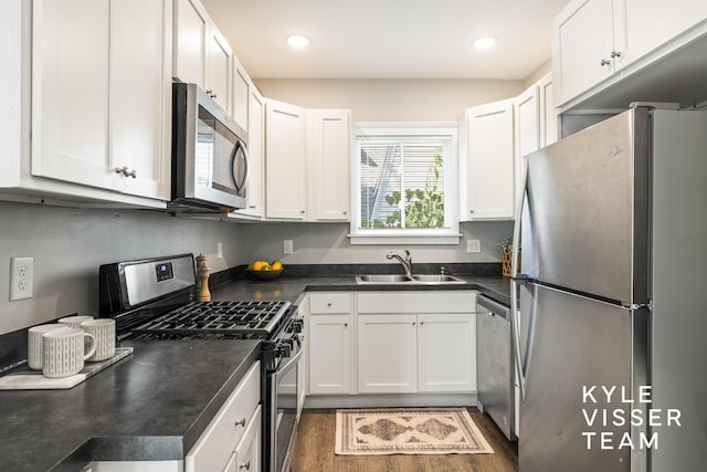 135 Houseman Ave NE, Grand Rapids, MI 49503 - kitchen featuring appliances with stainless steel finishes, dark countertops, white cabinets, dark wood-type flooring, and recessed lighting