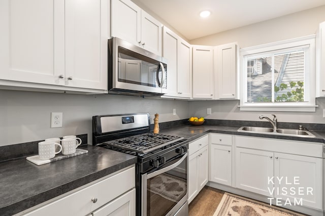 135 Houseman Ave NE, Grand Rapids, MI 49503 - kitchen featuring stainless steel appliances, dark countertops, white cabinetry, wood finished floors, and recessed lighting