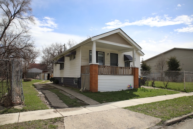 bungalow featuring a front lawn, fence, and covered porch