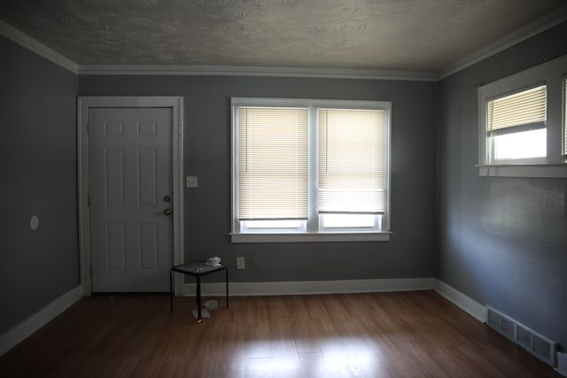 foyer featuring visible vents, baseboards, ornamental molding, a textured ceiling, and wood finished floors
