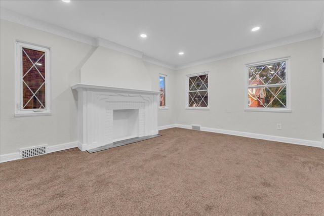unfurnished living room featuring baseboards, carpet flooring, visible vents, and crown molding