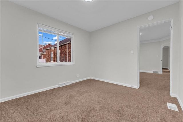 carpeted empty room featuring baseboards and visible vents