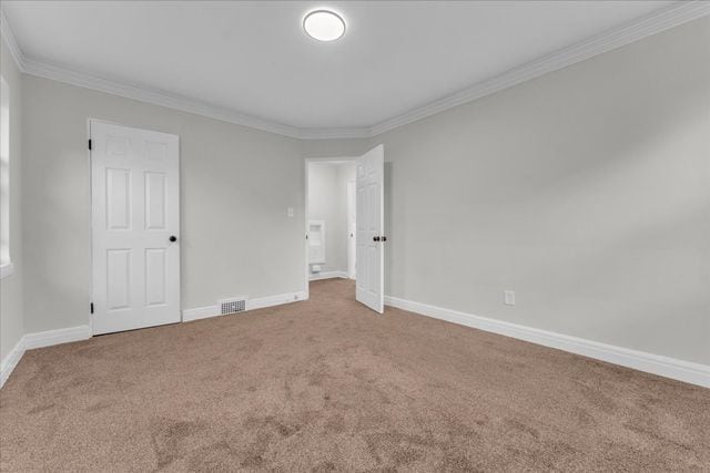 unfurnished room with baseboards, visible vents, crown molding, and carpet
