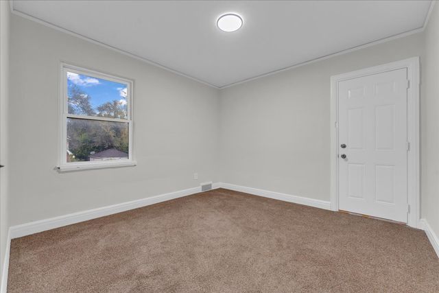 carpeted empty room with baseboards and crown molding