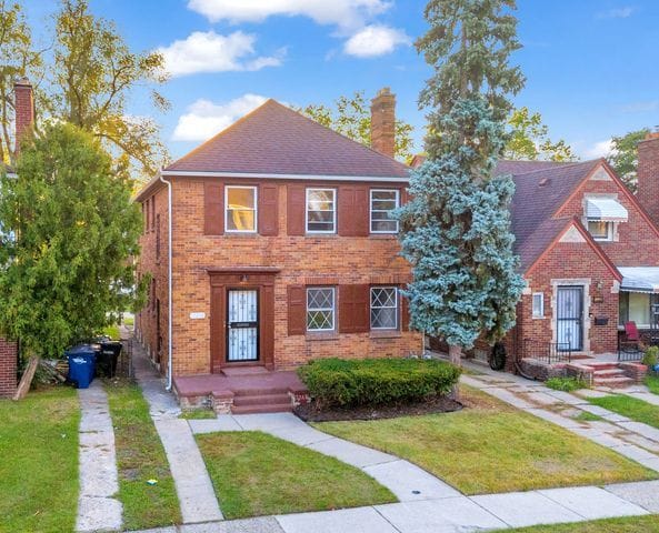view of front of property with a front lawn, a chimney, a shingled roof, and brick siding