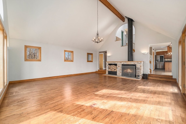 unfurnished living room featuring beamed ceiling, an inviting chandelier, high vaulted ceiling, wood finished floors, and baseboards