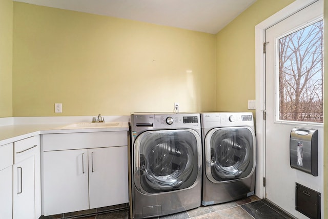 clothes washing area featuring washing machine and dryer, a sink, and cabinet space