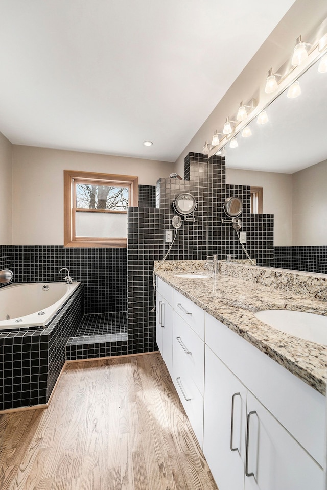 bathroom with a sink, walk in shower, double vanity, and a tub with jets