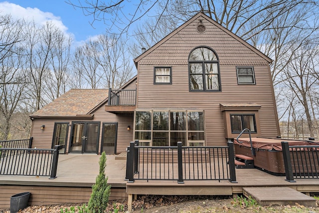 back of house featuring a shingled roof, a balcony, and a hot tub