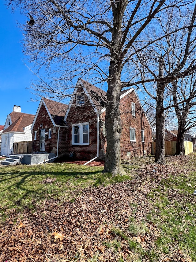 view of front of property featuring a front yard, brick siding, and fence