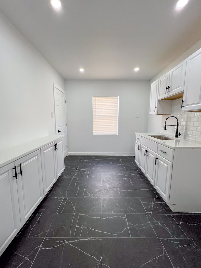 kitchen featuring marble finish floor, a sink, white cabinets, and recessed lighting