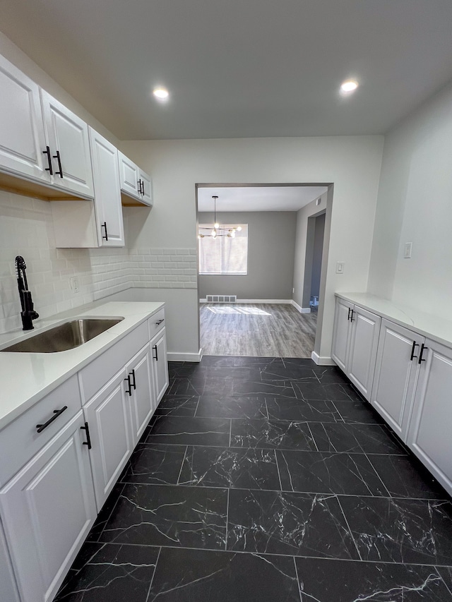 kitchen with a sink, visible vents, white cabinetry, and marble finish floor