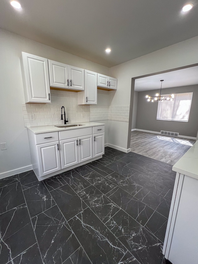 kitchen featuring light countertops, visible vents, baseboards, and a sink
