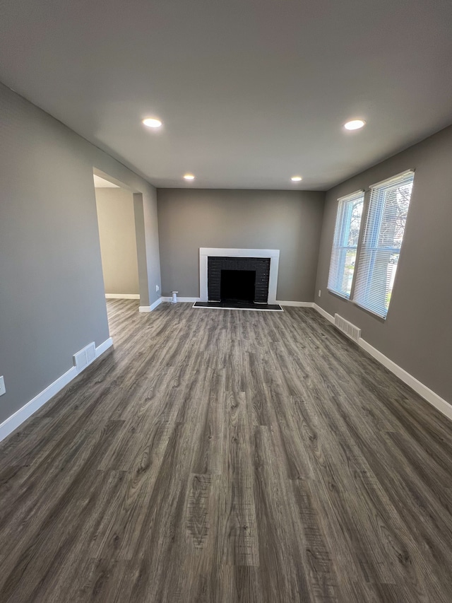 unfurnished living room featuring visible vents, recessed lighting, and a brick fireplace