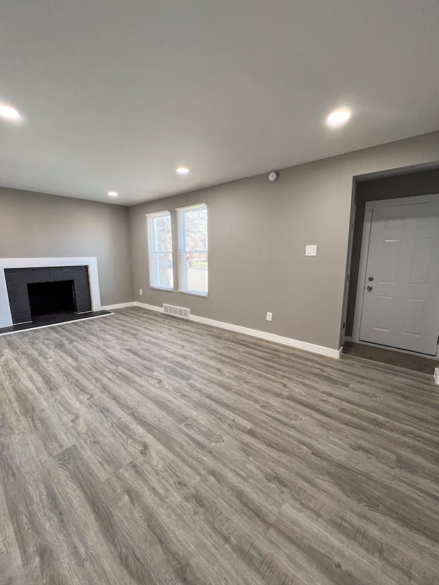 unfurnished living room featuring wood finished floors, a fireplace, visible vents, and recessed lighting