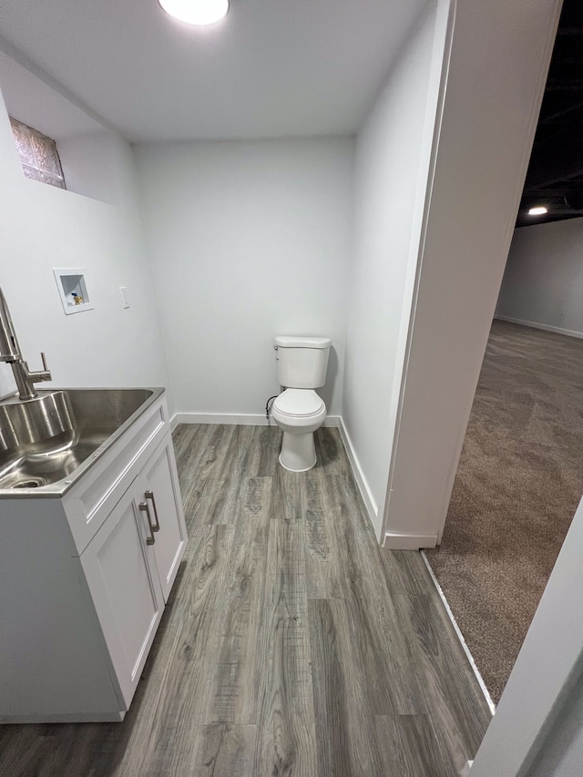 half bathroom with vanity, baseboards, toilet, and wood finished floors