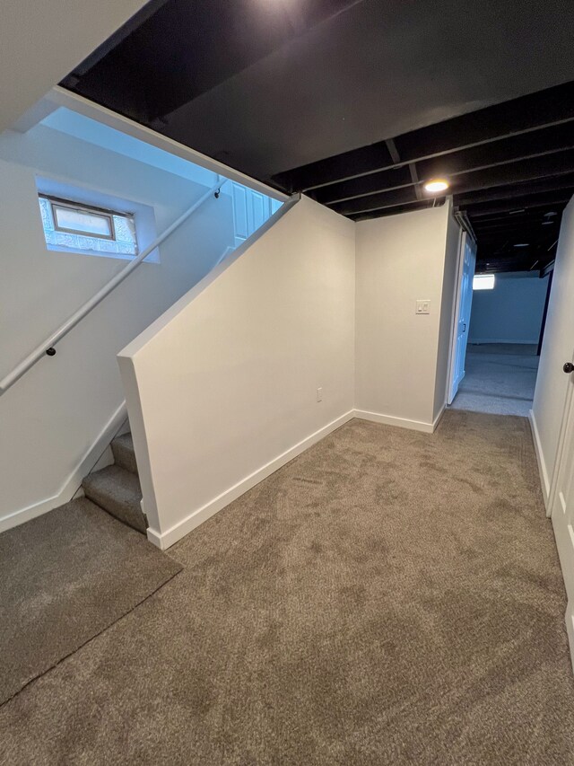 below grade area featuring stairs, carpet, and baseboards