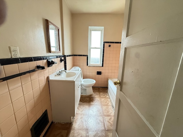 bathroom featuring visible vents, tile walls, a wainscoted wall, vanity, and toilet