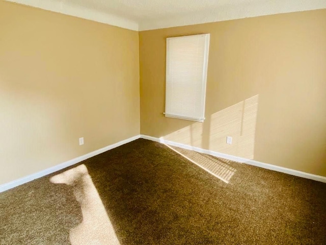 empty room with dark colored carpet and baseboards