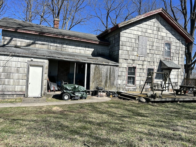 rear view of property with a chimney, a wooden deck, and a yard