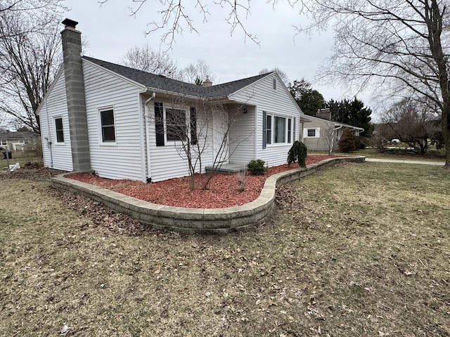 617 Cherry Ave, Big Rapids, MI 49307 - view of side of home featuring a lawn, a shingled roof, and a chimney