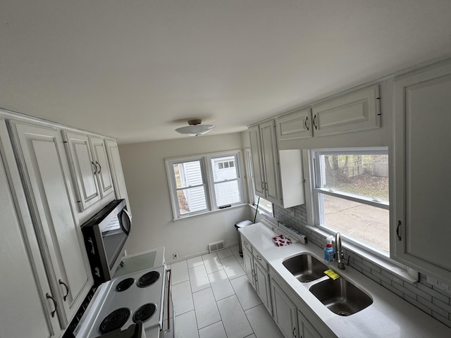 617 Cherry Ave, Big Rapids, MI 49307 - kitchen with decorative backsplash, visible vents, plenty of natural light, stainless steel microwave, and a sink