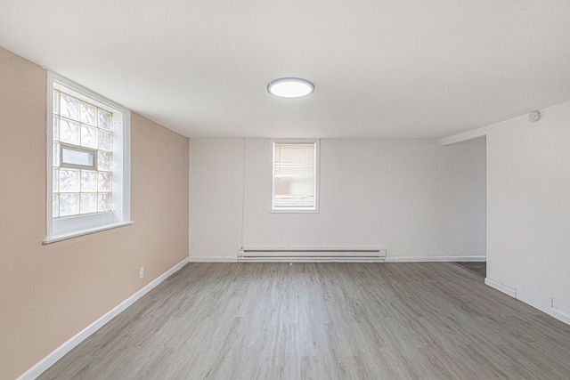 unfurnished room featuring a baseboard radiator, baseboards, and wood finished floors