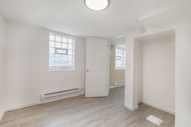 unfurnished bedroom featuring baseboard heating, light wood-type flooring, and multiple windows