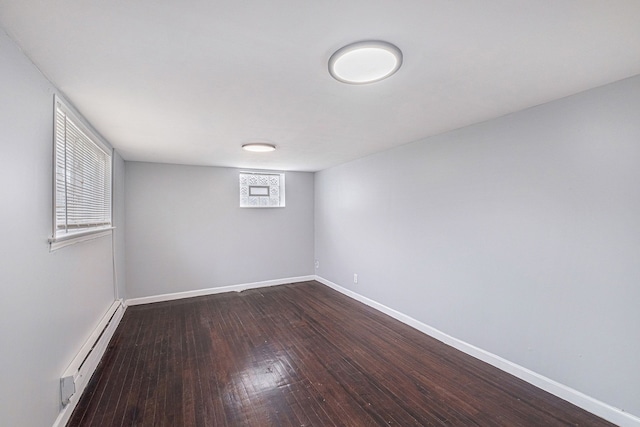 below grade area with baseboards, a baseboard heating unit, and dark wood-style floors