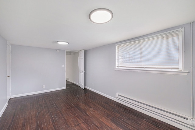below grade area with baseboard heating, wood-type flooring, and baseboards