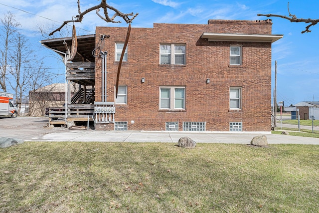 view of home's exterior featuring stairs, brick siding, and a lawn