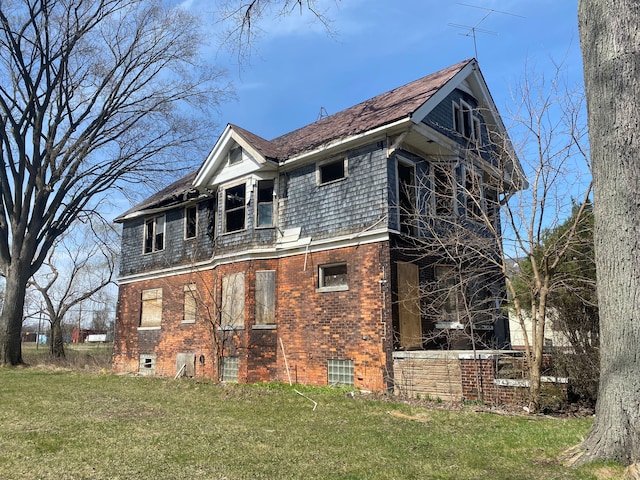view of side of home with brick siding and a lawn
