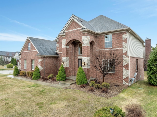 traditional-style home featuring a front yard, brick siding, and a shingled roof