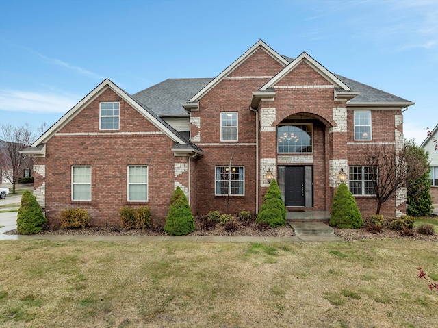 traditional-style home with a shingled roof, brick siding, and a front yard