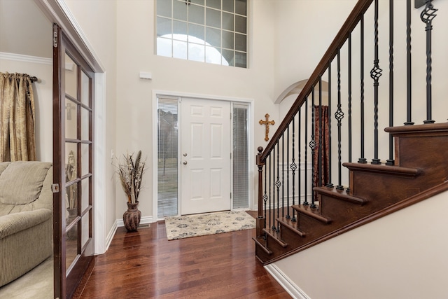 entryway featuring a towering ceiling, stairway, wood finished floors, and baseboards