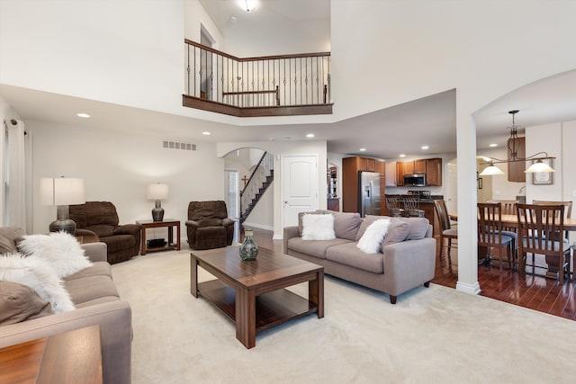 living room with visible vents, a towering ceiling, arched walkways, and recessed lighting