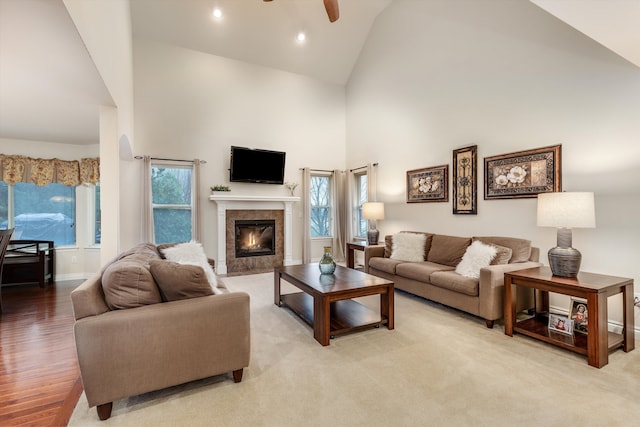 living area featuring light wood-style flooring, recessed lighting, ceiling fan, high vaulted ceiling, and a tile fireplace