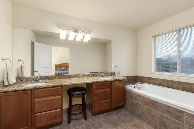 ensuite bathroom featuring a sink, double vanity, and a bath