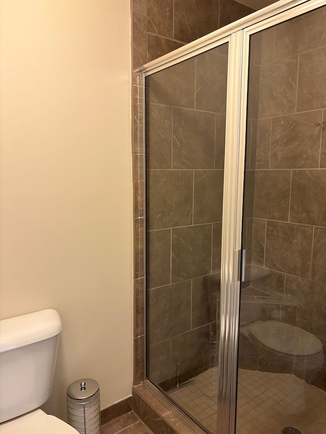 bathroom featuring tile patterned floors, toilet, baseboards, and a stall shower